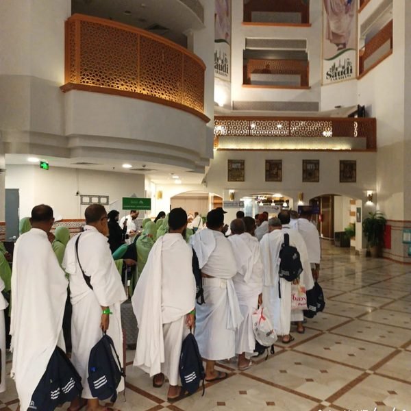 حجاج بالإحرام في صف داخل بهو السكن